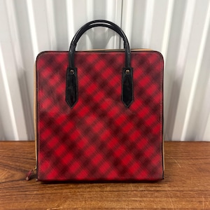 May include: A red and black plaid pattern tote bag with black handles and a gold zipper. The bag is rectangular with a structured design, suitable for carrying various items.