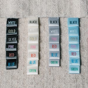 May include: A set of six colour swatches, each with a different colour label. The colours are black, white, gold, pink, red, blue, and green. The swatches are arranged in a row from left to right.