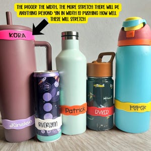 May include: Five assorted water bottles and a beverage can, each featuring a colourful silicone name band. The text on the yellow sign reads: The bigger the width, the more stretch there will be. Anything beyond 4in in width is pushing how well these will stretch.