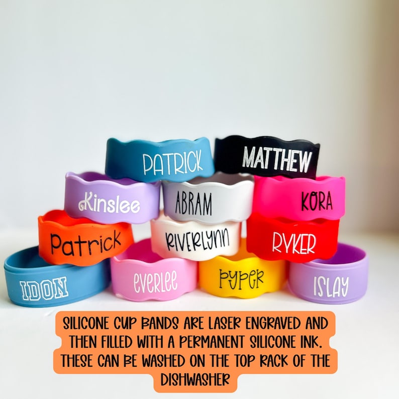 May include: A collection of colourful silicone cup bands featuring laser-engraved names including Patrick, Kinslee, Abram, Riverlynn, Matthew, Kora, Ryker, Idon, Everlee, Pyper, and Islay. The text states these are laser engraved and dishwasher safe.