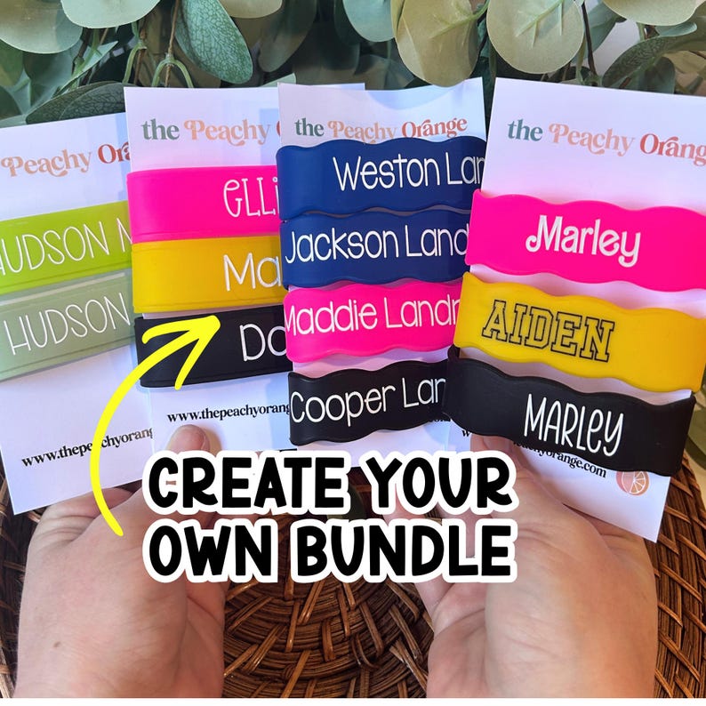 May include: A collection of colourful, wavy silicone wristbands featuring personalised names in white or black text. The bands are displayed on white cards labelled with the Peachy Orange brand name, showcasing various bright colours like neon pink, yellow, and black.