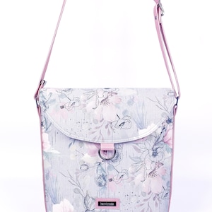 May include: A light gray and pink floral print crossbody bag with a pink strap and a silver metal ring.