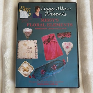 Op de afbeelding: Een dvd-hoes met de titel "Missy's Floral Elements" van Lizzy Allen. De cover toont verschillende borduurontwerpen, waaronder een roze kledingstuk, een hartvormig ontwerp en een turquoise loper met bloemaccenten. De achtergrond is een zachte, gebroken witte stof.