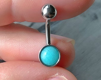 May include: A silver belly button ring with a turquoise gem. The ring is made of surgical steel and is suitable for body piercing.