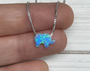 May include: A silver chain necklace with a blue opal elephant pendant. The elephant is small and detailed, with a textured surface.