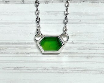 May include: A silver chain necklace with a green hexagonal pendant.