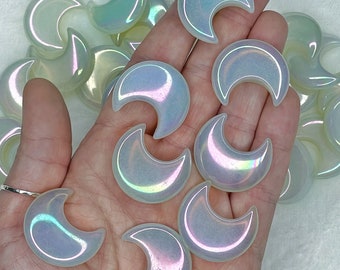 May include: A collection of iridescent white crescent moon shaped crystals. The crystals are smooth and polished, with a subtle shimmer.