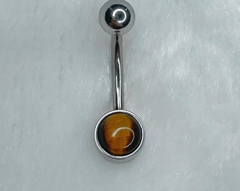 May include: A silver belly button ring with a round, brown and gold tiger's eye gemstone.