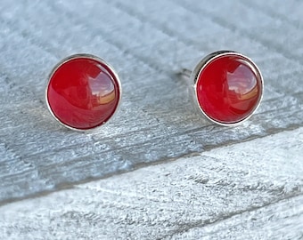 May include: A pair of silver stud earrings with red round gemstones.