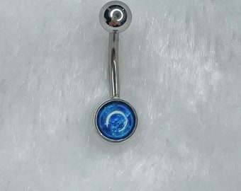 May include: A silver belly button ring with a blue and white crescent moon design.