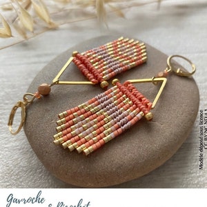Peut inclure: Une paire de boucles d'oreilles en perles de pêche et d'or avec une forme triangulaire et un design en frange. Les boucles d'oreilles sont suspendues à des crochets dorés.