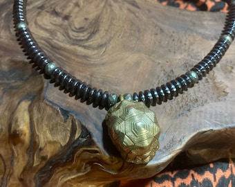 Collana in ottone con campanella in guscio di tartaruga.
