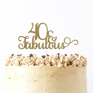 May include: Gold glitter cake topper with the text "40 & Fabulous" on a beige frosted cake.