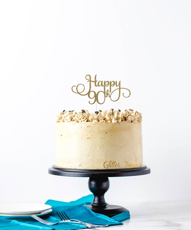 May include: A white cake with brown frosting and a gold glitter topper that says "Happy 90th".