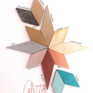 Pu&ograve; includere: Una collezione di piastrelle a forma di diamante disposte a stella, etichettate con colori tra cui black gold glitter, gold glitter, gold, champagne, natural, sanded natural, silver, pink champagne, copper, rose gold, sea mist e turquoise.