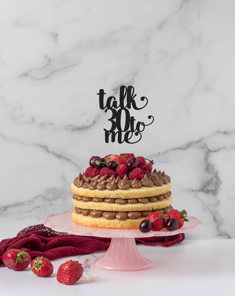 May include: A three-tiered cake decorated with chocolate frosting and fresh berries. The cake is topped with a black glitter cake topper that says "talk 30 to me".