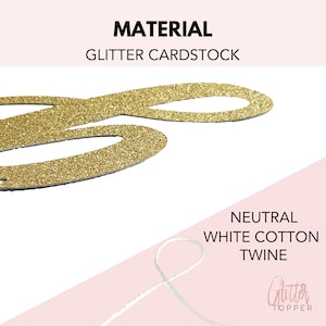 May include: Gold glitter cardstock number two with white twine for hanging.  The number is made of glitter cardstock and is attached to a white twine string.  The twine is neutral white cotton twine.  The number is a two, and the twine is attached to the top of the number.  The number is on a white background.