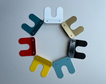 May include: Seven different colored metal hooks in the shape of a U, arranged in a circle. The hooks are red, blue, yellow, green, white, black, and gold.