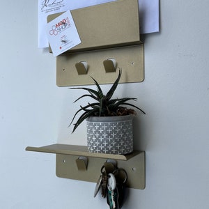 May include: A white ceramic mug with a black handle and the text "But First, Coffee" in a bold, black font. The mug is set against a blurred background, suggesting a cozy setting.