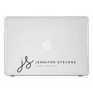 May include: A white laptop computer with a sparkly, glittery finish. The laptop has a black Apple logo and a black sticker with the text "js Jennifer Stevens Home Staging".