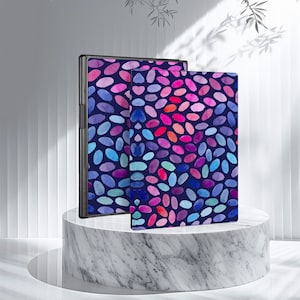 May include: Two black e-readers with colorful watercolor patterns of pink, blue, and purple dots on a white marble surface.