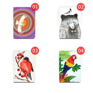 May include: Four different designs for a notebook cover. The first design features a white bird with a purple, orange, and yellow background. The second design features a black bear with a small bird on its head. The third design features a red bird on a branch with white berries. The fourth design features a red and blue parrot on a green leaf.