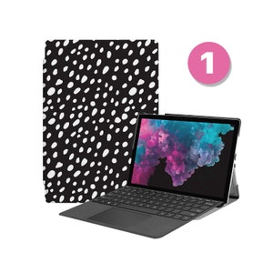 May include: A black and white spotted laptop case with a black laptop with a keyboard and a pink and purple cloud background on the screen.