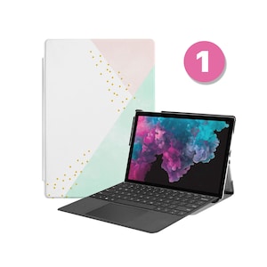 May include: A black laptop computer with a white and light blue geometric patterned case. The laptop is open and the screen displays a pink and purple abstract image. The case has gold dots.