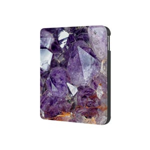 May include: Close-up of a cluster of amethyst crystals. The crystals are a deep purple colour and have a variety of shapes and sizes. The crystals are arranged in a natural formation, with some of the crystals overlapping each other.
