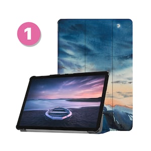Może przedstawiać: Tablet z czarną obudową i ekranem wyświetlającym krajobraz z łodzią na plaży o zachodzie słońca. Obudowa ma akwarelowy wzór niebieskiego nieba z chmurami i rogalem księżyca.