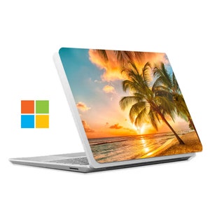 May include: A white laptop with a sunset beach scene on the back. The scene features palm trees, a sandy beach, and a bright orange sunset over the ocean.