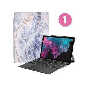 May include: A black laptop computer with a white marble design case. The laptop is open and the screen is displaying a colorful abstract image. The laptop is sitting on a white surface.