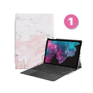 May include: A black laptop with a pink and white marble design case. The laptop is open and the screen shows a colorful abstract image. The number 1 is written in white on a pink circle.