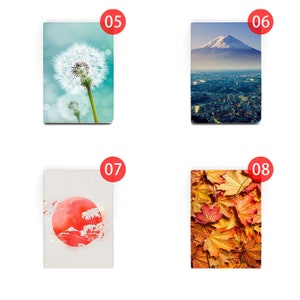 May include: Four different designs for a notebook cover. The first design features a dandelion with a blue and white background. The second design features Mount Fuji with a city skyline in the foreground. The third design features a red watercolor circle with a mountain and waves inside. The fourth design features a close-up of orange and yellow autumn leaves.