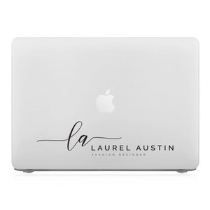 May include: A white laptop with a black logo that says "la LAUREL AUSTIN FASHION DESIGNER".