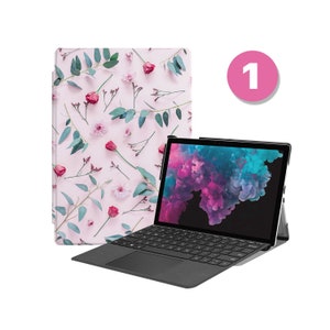 May include: A black laptop with a floral patterned case. The laptop has a keyboard and a trackpad. The screen is displaying a colorful abstract image. The case is pink with green leaves and red flowers.