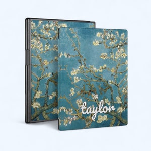 Può includere: Una custodia per telefono blu e bianca con fiori e il nome "taylor" scritto in corsivo bianco.