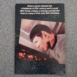 May include: A black and white greeting card with a photo of a man with pointed ears. The text on the card reads "History banks indicate that inhabitants of 20th century earth would often times undergo a strange suicidal-like ritual on many of their post 30th birthdays."