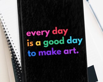 Puede incluir: Cuaderno negro con el texto "every day is a good day to make art." en colores arcoíris.