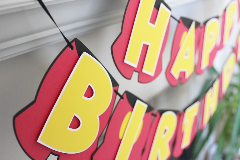 May include: A red, yellow, and black paper banner that reads "Happy Birthday".
