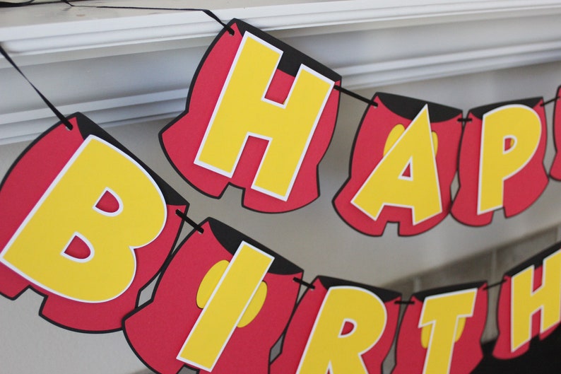 May include: A red and yellow banner with the words "Happy Birthday" in a Mickey Mouse-inspired font.