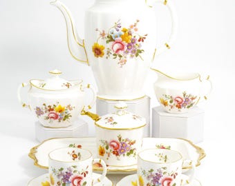 以下が含まれることがあります： 白い磁器のティーセット。花柄のデザイン。コーヒーポット、砂糖入れ、クリーマー、ソーサー付きティーカップ2客、サービングトレイが含まれます。各ピースの縁は金色のトリムで装飾されています。