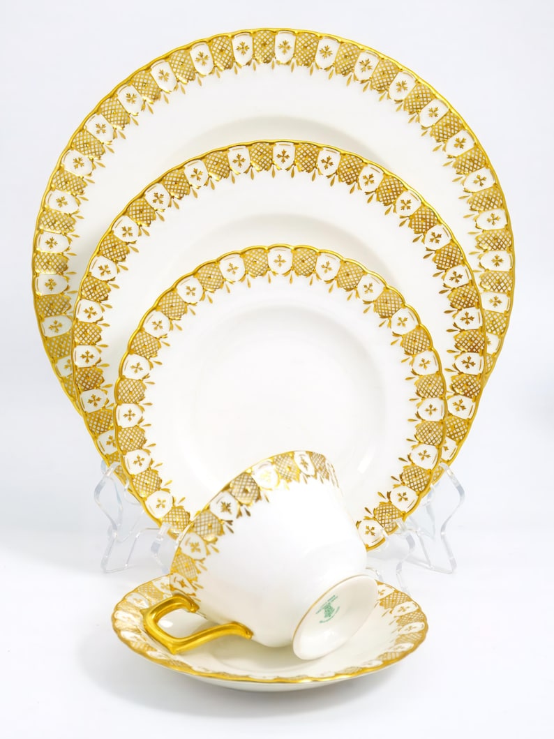 Pu&ograve; includere: Un set di stoviglie in porcellana bianca con bordi dorati. Il set comprende una tazza da t&egrave;, un piattino e tre piatti di diverse dimensioni.
