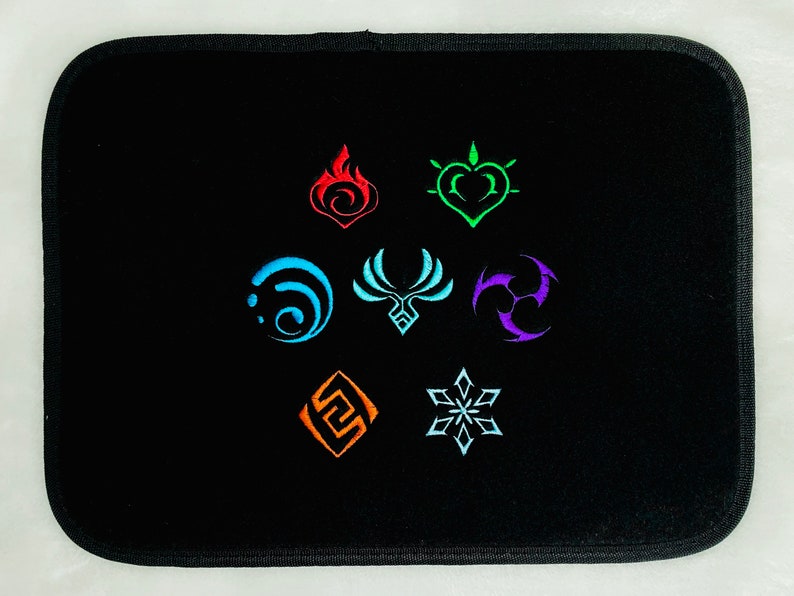 Op de afbeelding: Zwarte muismat met zeven geborduurde symbolen in verschillende kleuren: blauw, rood, oranje, groen, paars, lichtblauw en wit. De symbolen zijn in een cirkel gerangschikt.
