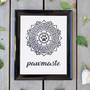 May include: Black and white framed print with a mandala design featuring a paw print in the centre. The text "pawmaste" is written below the mandala.