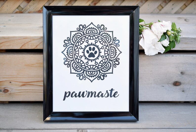 May include: Black and white framed print with a mandala design featuring a paw print in the centre. The text "pawmaste" is printed below the mandala.
