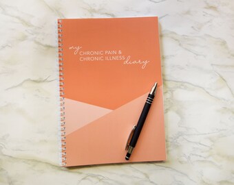 Może przedstawiać: Szyty spiralnie notes z pomarańczową okładką i napisem "my CHRONIC PAIN & CHRONIC ILLNESS diary" w kolorze białym. Na notesie leży czarny długopis.