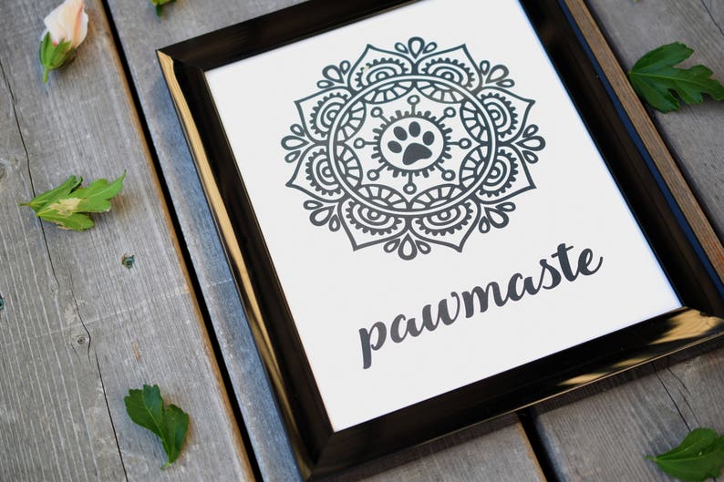 May include: Black and white framed print with a mandala design featuring a paw print in the centre. The text "pawmaste" is written below the mandala.