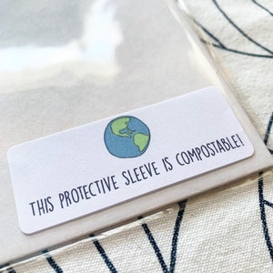 May include: A white label with a green and blue globe illustration and the text "THIS PROTECTIVE SLEEVE IS COMPOSTABLE!"