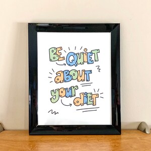 Puede incluir: Una impresi&oacute;n enmarcada en negro con el texto "Be Quiet About Your Diet" en letras coloridas y juguetonas. El texto est&aacute; escrito en una fuente caprichosa con flechas y garabatos.